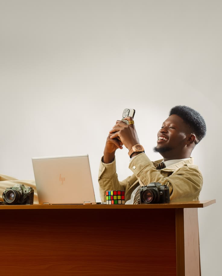 Créateur de contenu consultant son téléphone devant son ordinateur et son matériel photo